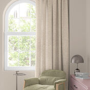 Raam met kleurrijk bloemengordijn in rood, oranje en blauw, groene stoel en tafeltje met lamp